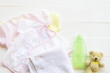 Yeni doğmuş bebek ve kız çocuğunun pamuklu giysileri vücut bakımı için sıvı sabunla temizlenmiş cilt bakımı için düz arka plan beyaz ahşap üzerine yatıyordu.