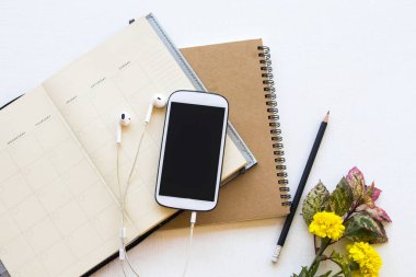 iş için cep telefonu ve çiçek düzenleme için dizüstü bilgisayarı olan dizüstü bilgisayar planlayıcısı arkaplan beyaz üzerine yatar 