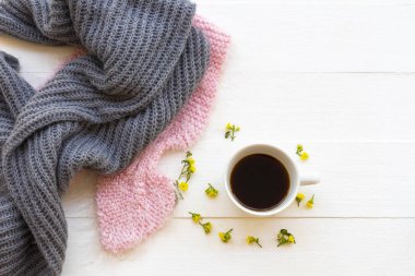 Sıcak kahve, örgü ören yün atkı ve sarı çiçekli kadın kış mevsimi düzenlemelerinde rahatla.