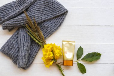 Güneş kremi spf50 güzellik makyajı cilt için örgü ören kadın yün atkıyla kış mevsimi düzenleme düz beyaz üzerine yatıyordu