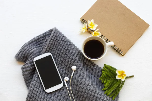 notebook ,mobile phone ,coffee and knitting  wool scarf of lifestyle woman relax in winter season decoration on background white wooden