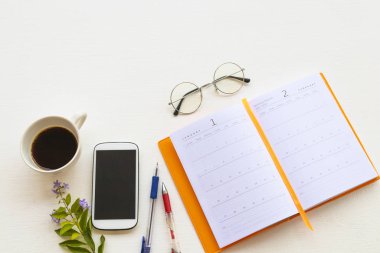 Not defteri planlayıcısı, iş için cep telefonu sıcak kahve espresso düzenleme düz arka planda beyaz ahşap üzerinde ofis tarzı