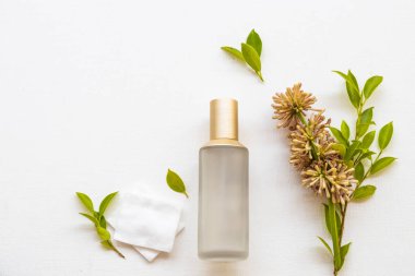 Terapi, pamuk doğal kozmetik içeren ilk serum tonerleri cilt için bitkisel sağlık hizmetleri sunar. Kadın yüzü güzelliği ve çiçek düzenlemesi düzleştirici arka planda bembeyaz yatar. 