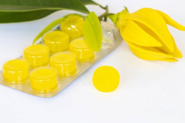 Öksürük ağrısı boğaz pastilleri. Renkli bitki özü. Sarı çiçekler, ylang ylang düzenleme. 