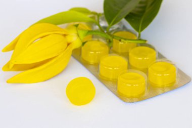 Öksürük ağrısı boğaz pastilleri. Renkli bitki özü. Sarı çiçekler, ylang ylang düzenleme. 