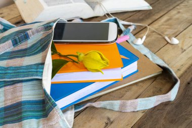 Not defteri, günlük ve cep telefonu içinde sözlük kitabı olan bez çantada öğrenci düzenleme dairesi arka plandaki ahşap üzerinde yatıyordu.