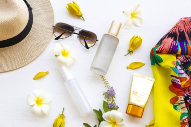 Güneş kremi spf50, kolajen su spreyi, tonerler serum tedavisi kozmetik sağlık hizmetleri sarı atkı, güneş gözlüğü ve yaşam tarzı kadın düzenleme şapkası bembeyaz üzerine yatıyordu. 