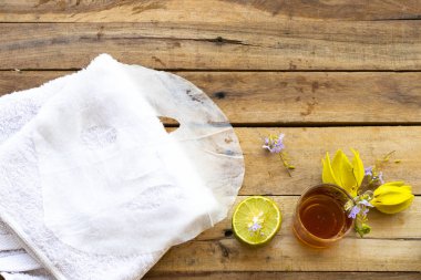 Doğal aroma örtüsü, bal özütü bitkisel bitki sağlığı hizmetleri cilt için yüz maskesi ve çiçek ylang ylang, yüz havlusu düzenleme düz arka plan ahşap üzerine yatıyordu