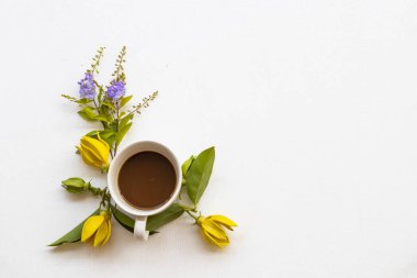 Sarı çiçekli sıcak kahve yaşam tarzı düzenleme ylang düz arka planda beyaz ahşap üzerine yatar kartpostal tarzı