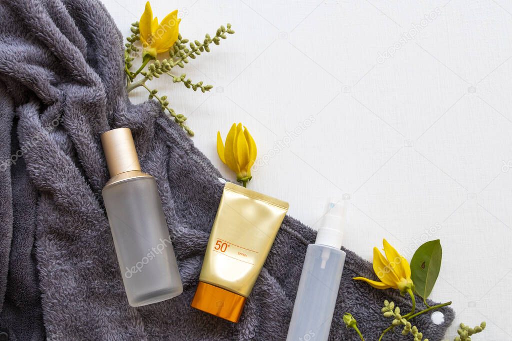 sunscreen spf50, collagen water spray and toners serum cosmetics beauty health care for skin face with blanket ,yellow flowers ylang ylang of lifestyle woman relax in winter arrangement flat lay style