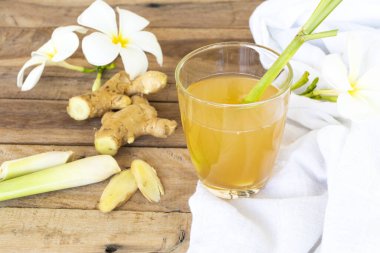 Sıcak zencefilli su bitkisel sağlıklı içecekler zencefil dilimli, limonlu ve çiçekli öksürük yaraları için sağlık hizmetleri Frangipani yerel flora Asya düzenlemesi düz arka plan ahşap üzerinde yatıyordu