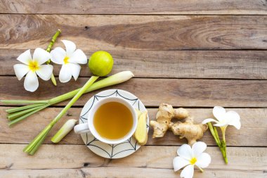 Sıcak zencefilli su, bitkisel sağlıklı içecekler zencefil dilimi, limon otu, limon ve çiçekli öksürük ağrısı için sağlık hizmeti, frangipani yerel flora Asya düzenlemesi düz arka plan ahşap üzerine yatıyordu.