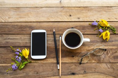 Cep telefonu, sıcak kahve espresso ve mor çiçekler, sarı çiçekler ylang ylang düzenleme düz zemin üzerinde yatıyordu ahşap 
