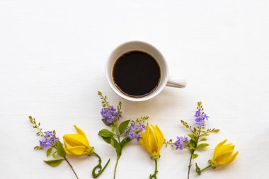 Sarı çiçekli sıcak kahve espresso yaşam tarzı düzenleme ylang düz arka plan beyaz üzerine yatar 