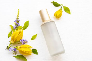 Terapi ilk serum tonerleri doğal kozmetik ürünleri cilt için bitkisel sağlık hizmetleri kadın yüzü güzelliği ve sarı çiçek ylang ylang düzenleme düz arka plan beyaz üzerine yatıyordu 