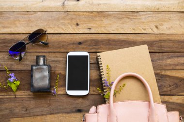 cep telefonu, güneş gözlüğü, çanta, parfüm, defter ve pembe el çantası koleksiyonu. Hayat tarzı kadın rahatla. Arka planda düz konum tarzı ahşap.