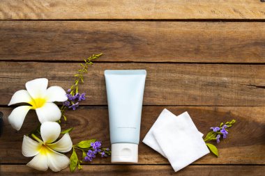 Temiz makyaj için pamuklu nemlendirici temizlik kremi cilt bakımı ve beyaz çiçekler için frangipani yaşam tarzı kadın düzenleme düz arka plan ahşap üzerine yatıyordu