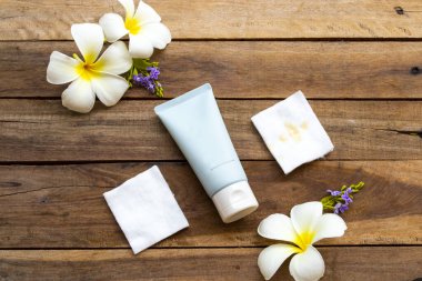 Temiz makyaj için pamuklu nemlendirici temizlik kremi cilt bakımı ve beyaz çiçekler için frangipani yaşam tarzı kadın düzenleme düz arka plan ahşap üzerine yatıyordu