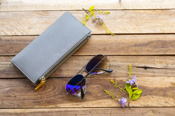 sunglasses ,purse and purple flowers collection of lifestyle woman relax arrangement flat lay style on background wooden