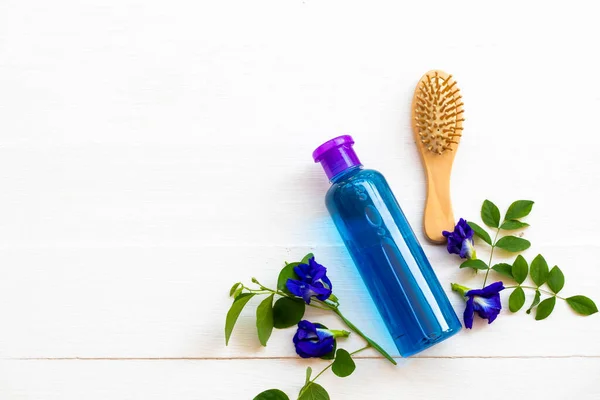 ハーブシャンプー抽出青花蝶エンドウ豆の健康管理用洗髪ブラシ櫛のライフスタイルの女性のクリーニング配置フラットレイスタイルの背景に白い木 — ストック写真