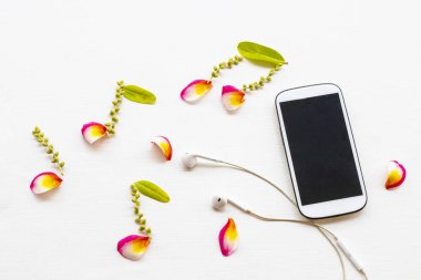 cep telefonu, kulaklık çiçek yapraklı frangipani aranjman müziği düz fon beyaz ahşap üzerine yatıyordu
