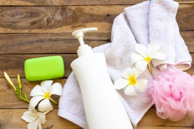 Vücut derisi için doğal bitkisel sıvı sabun sabunu sabunu, terry bezi, çiçek frangipani, ylang ylang düzenleme düz arka plan ahşap üzerinde yatıyordu