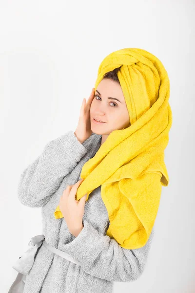 Carino donna in accappatoio grigio con asciugamano giallo sulla testa — Foto Stock