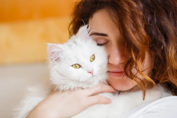 Schattig meisje met krullend haar knuffelen witte pluizige kat Stockafbeelding