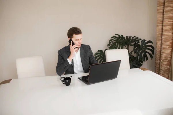 Bir bilgisayarda çalışan ve telefonda konuşurken çekici işadamı
