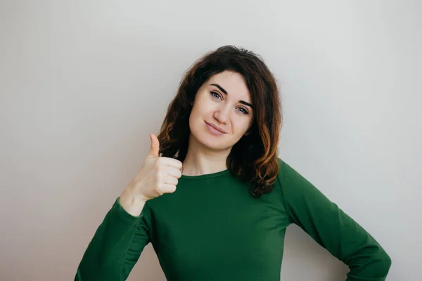 Gülümseyen genç ve güzel kadın üzerinde hafif bir artalanları başparmak gösterilmesini