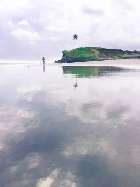 Reflectie van de hemel in de zee met een eenzame palmboom en een meisje op het eiland Bali. — Stockfoto