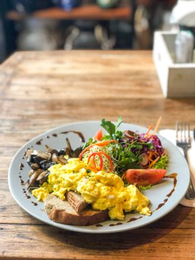 Ahşap bir masa bir kafede ekmek ve sebze ile omlet yanıyor.
