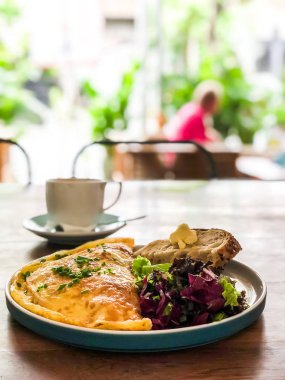Bir fincan kahve ile omlet bir kafede ahşap bir masa standı.