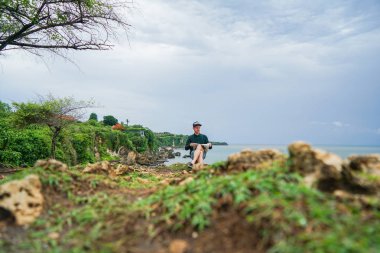 Bir adam bir uçurumun kenarında bir gazete okuyor. Bir görünümü sonsuz expanses plaj ve okyanus.