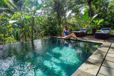 Genç bir kız ormanda bir sonsuzluk havuzu kenarında oturur. Ubud Bali Adası üzerinde gerçekleştirilen.