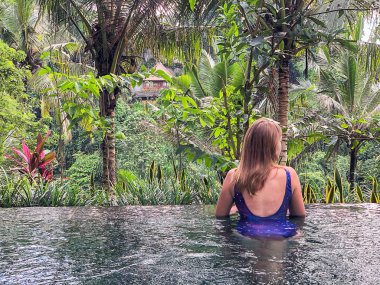 Genç bir kız ormanda sonsuzluk havuzunda yüzüyor. Ubud Bali Adası üzerinde gerçekleştirilen.