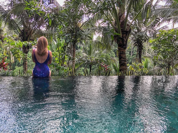 一个小女孩坐在丛林中的无边水池边上 采取在巴厘岛在乌布岛 — 图库照片