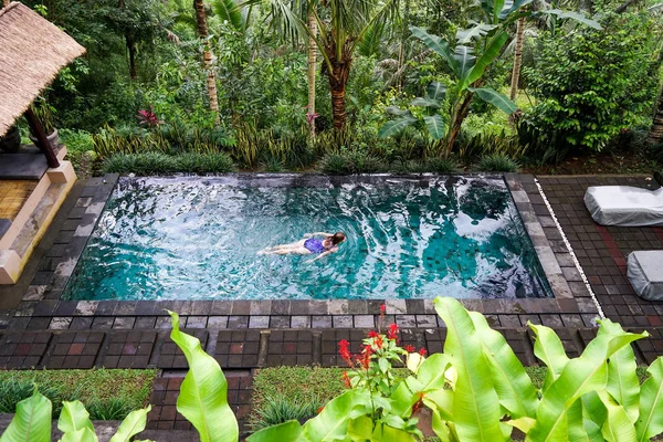 一个年轻的女孩漂浮在丛林中的无边水池里 采取在巴厘岛在乌布岛 — 图库照片