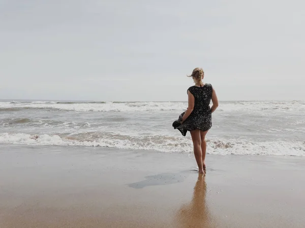 Girl in a developing in the wind dress on the background of the ocean.