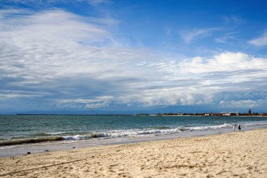 Mavi bir gökyüzü ve bir uçak kadar uçan ile bir plaj. Genç bir çift sahilde yürüyor. Bali Adası.