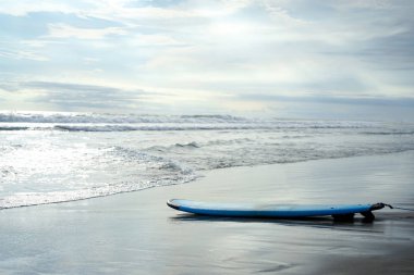 Sörf tahtası Bali Adası ıssız sahilde yatıyor.
