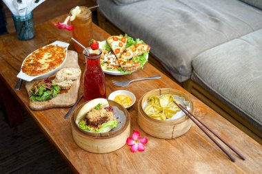 Raclette Tartiflette ve salata Chevre Chaud - Fransız mutfak. Bao burger ve kuşkonmaz tofu hamur tatlısı - Çin mutfağı. Kafede yan görünüm.