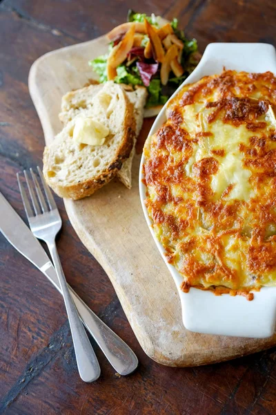 Raclette Tartiflette - french kitchen. Meat casserole on a wooden board. Raclette Tartiflette - french kitchen. Meat casserole on a wooden board. Top view