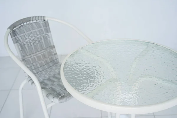 Transparent white table in the cafe. Rattan chair in the background. The whole room is white. Side view with copy space