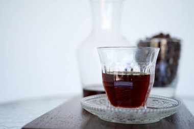 Bir ahşap tahta üzerinde şeffaf bir fincan kahve. Arka planda kahve aroması ve kahve çekirdekleri bir kavanoz var. Kopya alanı ile yakın çekim