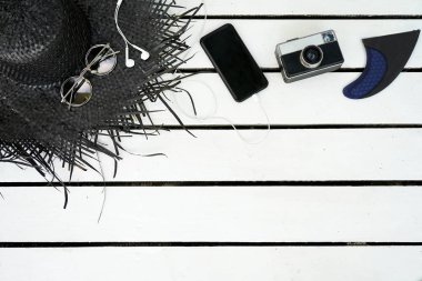 Beyaz ahşap arka plan üzerinde izole Minimal tarz düz yatıyordu. Yaz aksesuarları ile kadınsı Resepsiyon üstten görünüm: şapka, güneş gözlüğü, vintage fotoğraf makinesi, kulaklık, smartphone. Tatil seyahat app sunu