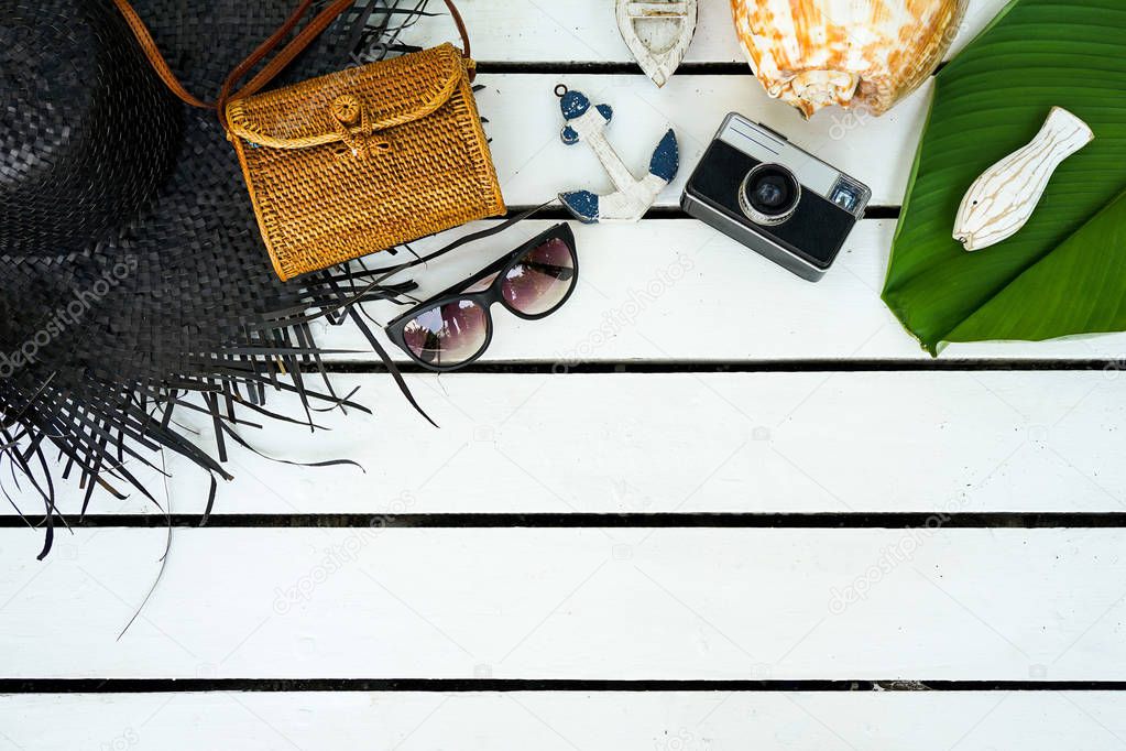Minimal styled flat lay isolated on white wood background. Feminine desk top view with summer accessories: hat, sunglasses, vintage photo camera, handbag, shell, anchor, boat, stones, fish