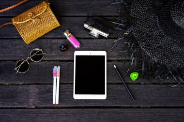 Koyu ahşap arka plan dijital tablet ile izole Minimal tarz düz yatıyordu. Kadın Danışma üstten görünüm aksesuarları ile: şapka, çanta, güneş gözlüğü, vintage fotoğraf makinesi, kulaklık, defter, kozmetik