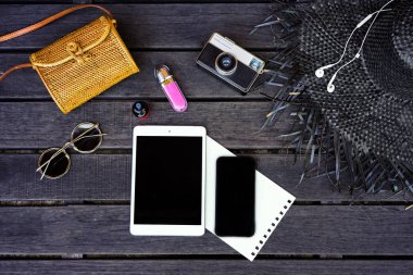 Koyu ahşap arka plan dijital tablet ile izole Minimal tarz düz yatıyordu. Kadın Danışma üstten görünüm aksesuarları ile: şapka, çanta, güneş gözlüğü, vintage fotoğraf makinesi, kulaklık, defter, kozmetik
