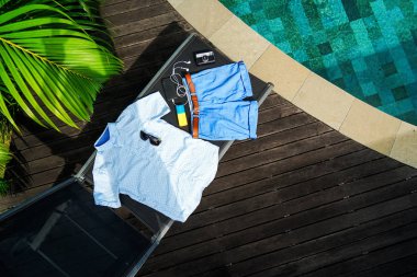Adam yaz giysileri düz yatıyordu üzerinde izole koyu ahşap arka plan Yüzme Havuzu ile kolaj. Yaz kıyafeti casual adam Resepsiyon üstten görünüm moda aksesuar: gömlek, şort, güneş gözlüğü, kamera, akıllı telefon